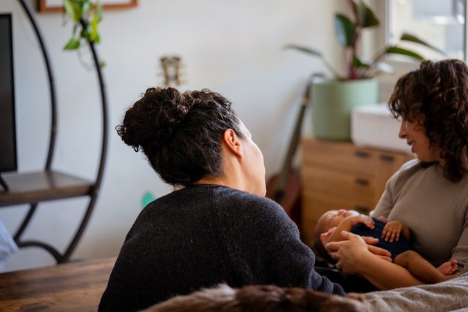 Female couple rocking baby to sleep in living room