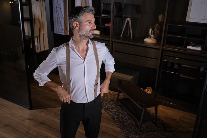 Confident bearded man trying on elegant clothes