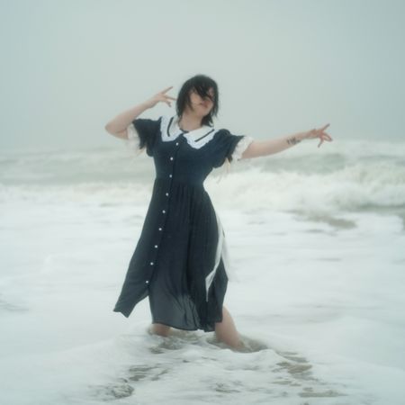 Woman in dark dress dancing on seashore