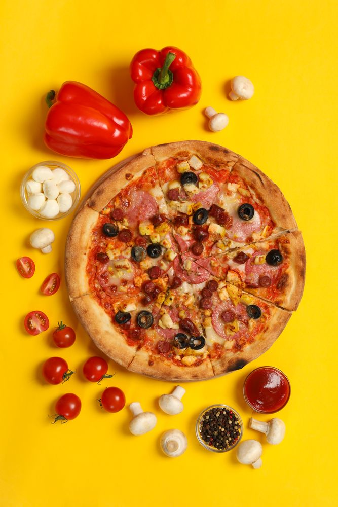 Tasty pizza and ingredients on yellow background