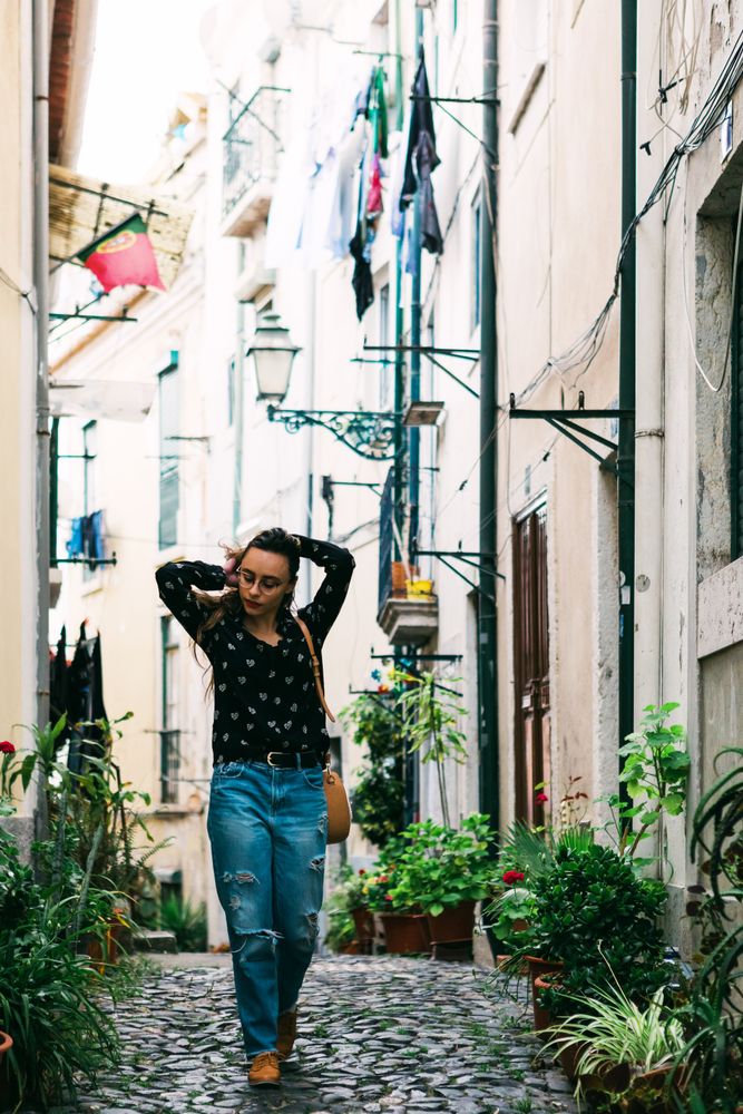 Young casual brunette walking on cobblestone street of old city