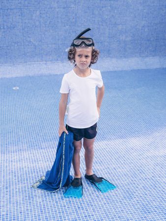 Discontent preteen bot in diving mask and flippers on pool