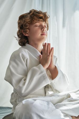 Dreamy boy meditating in Lotus pose