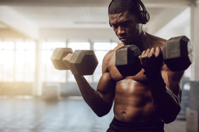 Bare chested man listening to music during workout at the gym