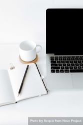 MacBook pro beside mug, pen and notebook 5XAB74
