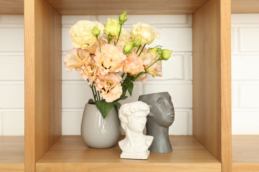 Wooden shelf with different items against brick wall