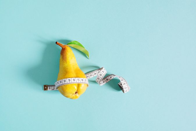 Yellow pear with measuring tape on blue background