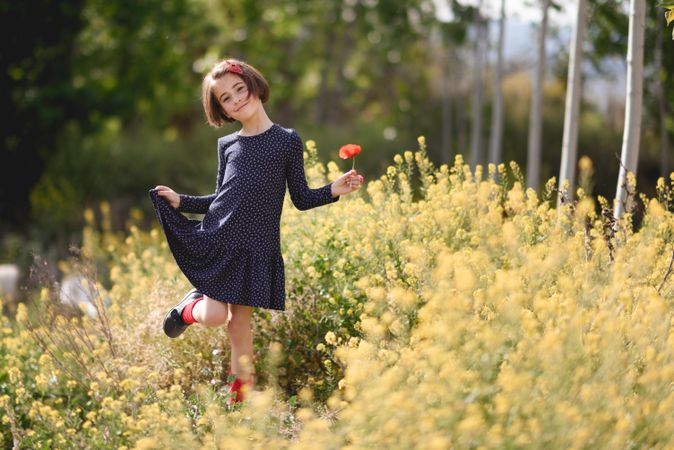 Girl with a red flower in a beautiful field surrounded by yellow flowers