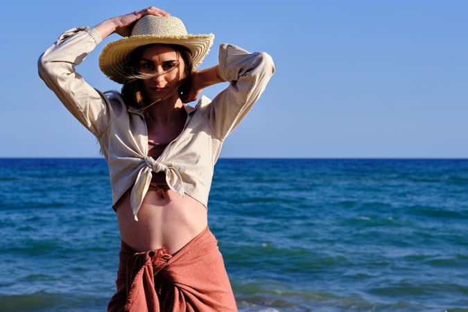 A fashion model with a hat at the beach before sunset