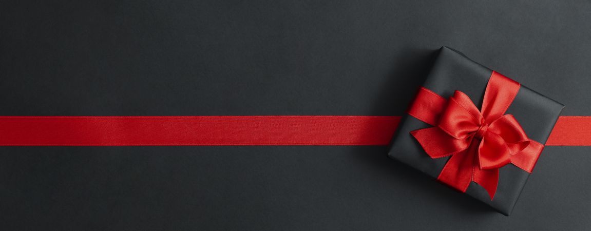 Gift box and red ribbon on dark background