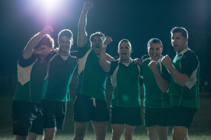 Rugby players celebrating a win at the sports arena at night