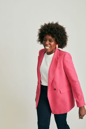 Woman in pink blazer with curly hair smiling