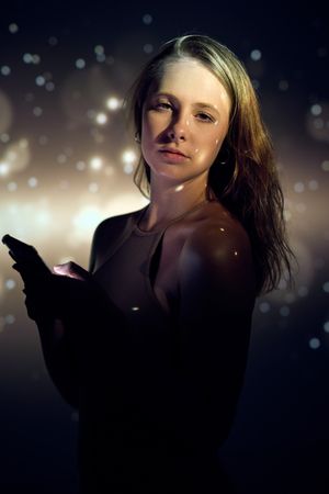 Woman with cellphone under golden sparks
