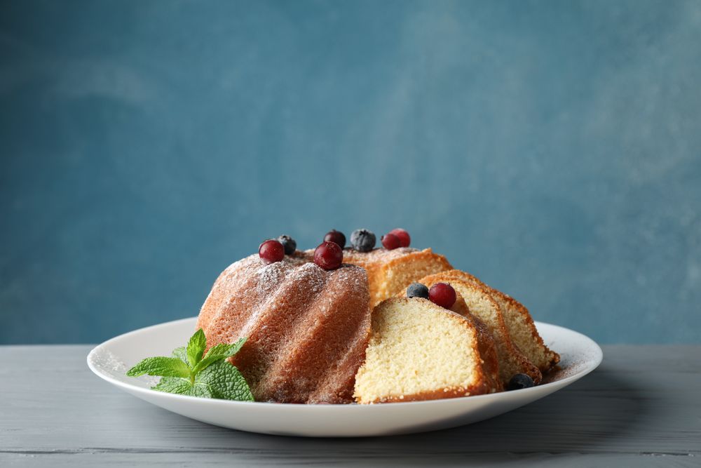 Cake with powder sugar and berries on wooden background, space for text
