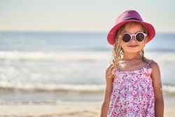 portrait of a girl with cap and sunglasses at the beach