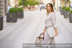 Chic woman in grey walking with laptop outside 5kRrmW