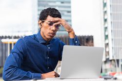 Serious male freelancer watching laptop in city