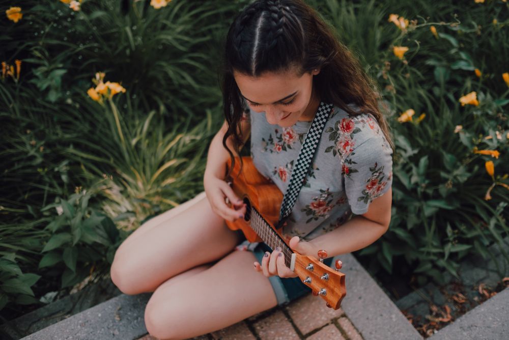 Happy modern woman playing ukulele