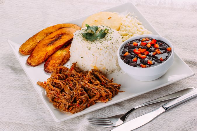 Homemade Venezuelan food. Traditional Venezuelan dish. Pabellon Criollo. White Rice, beans, Fried plantains, and Shredded beef