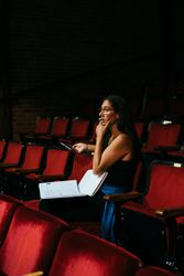Female director observing a scene from red theater rows