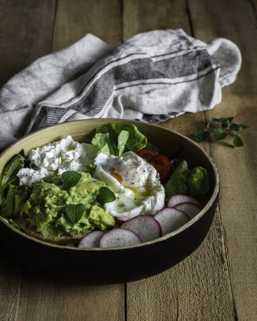 Tasty avocado bowl with vegetables on table