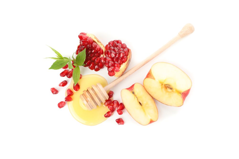 Looking down at honey dipper, pomegranate seeds, mint, and apple