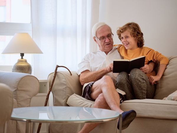 Cheerful grandfather with boy reading book