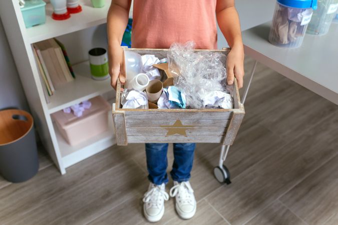 Girl showing a box of waste to recycle in ecology classroom