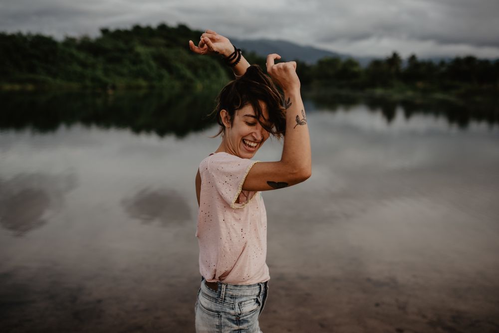 Cheerful woman dancing near lake