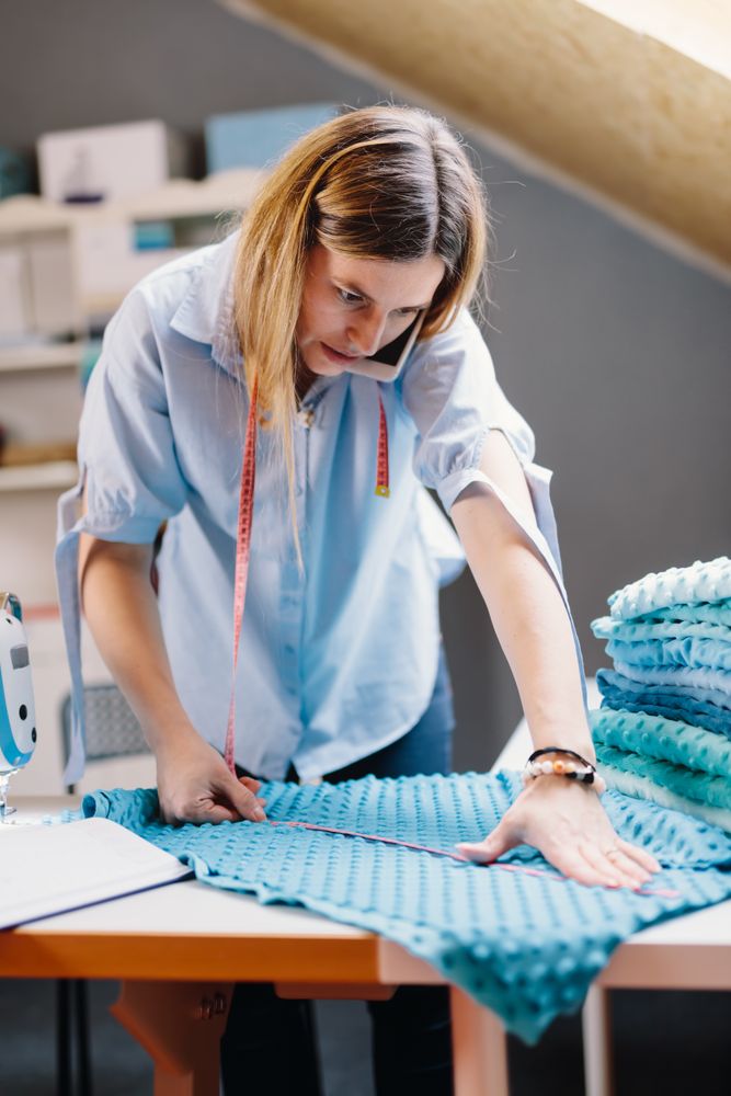 Concentrated seamstress talking on smartphone
