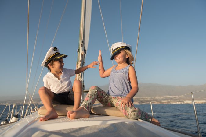 Smiling children sitting on deck of yacht in sea