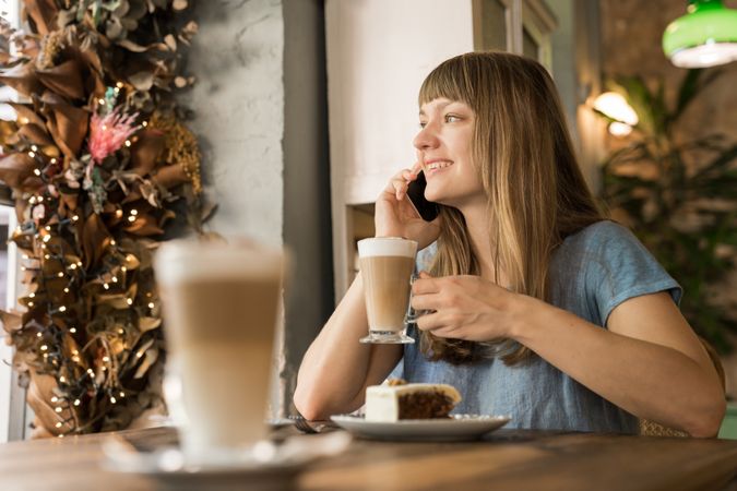 Cheerful woman talking on phone in cafe