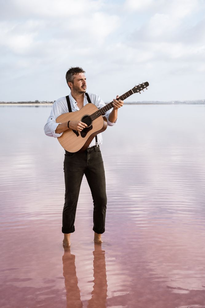 Inspired musician playing guitar at seaside
