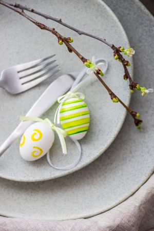 Top view of table setting for Easter dinner with egg ornaments and branch