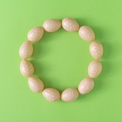 Wreath of Easter brown eggs on pastel green background