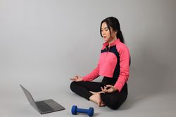 Young Woman Practicing Yoga with Online Lessons in Laptop at Home.