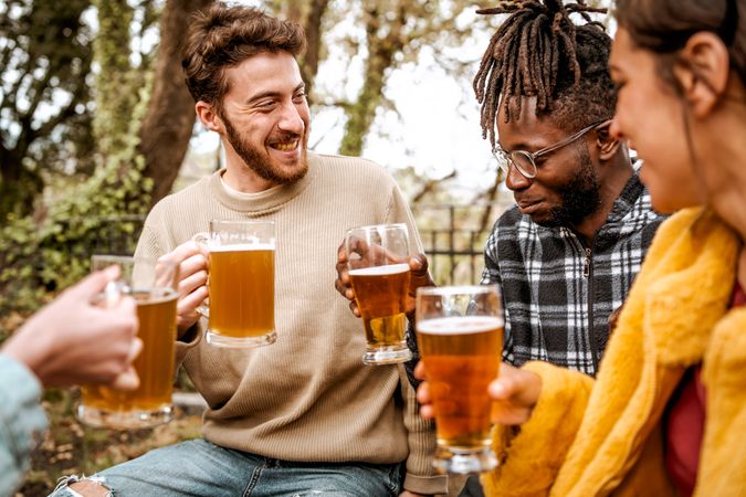 Multi-ethnic group of young friends having a party in the forest pub having fun talking and drinking beers