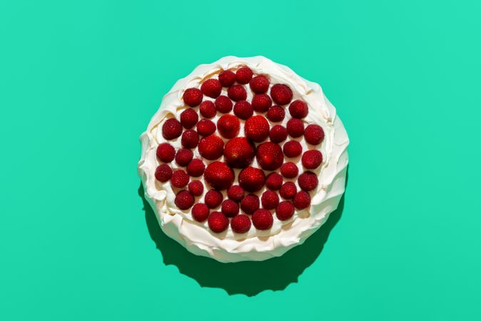 Pavlova cake with fresh berries, isolated on green background
