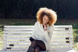 Laughing woman holding her phone and sitting the sun