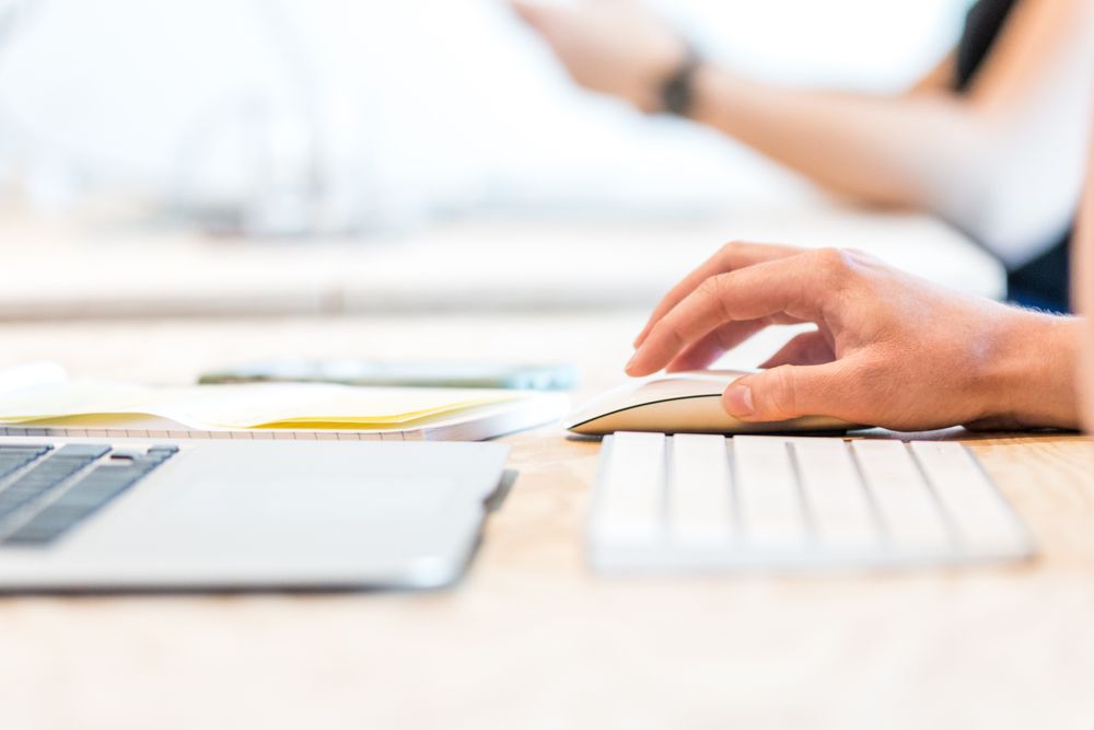 Cropped image of two people using computer keyboards on a desk