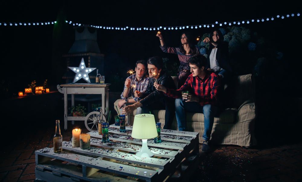 Fun friends holding sparklers at an outdoor party at night