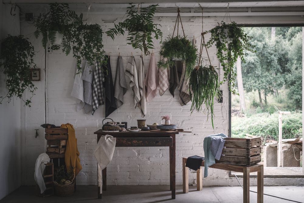 Table with flowers in vase on trays near towels hanging on thread