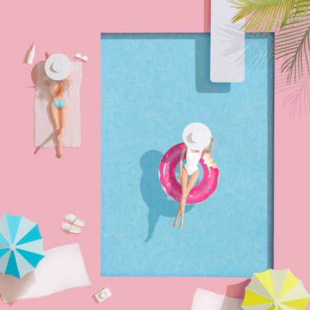Barbie-like doll in donut ring in pool, with friend at poolside with parasols and towels