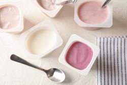 Composition with plastic cups with yogurt on table