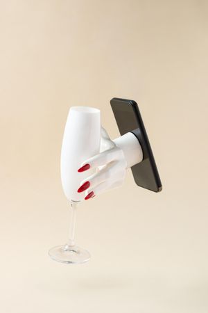 Woman’s hand reaching out of phone holding champagne glass