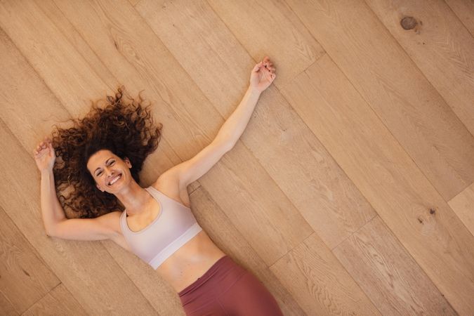 Directly above shot of a fit woman relaxing on a wooden floor at home