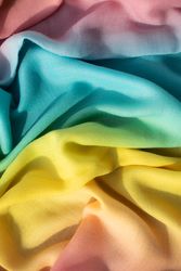Gradient yellow blue pink and green fabric wavy crumpled background texture.