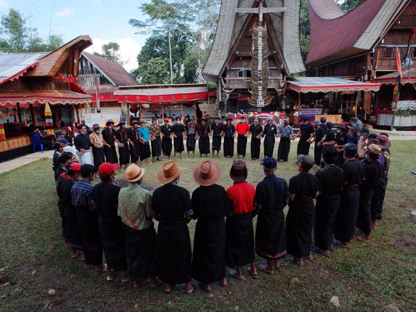 Tana Toraja people standing in circle beside their traditional wooden houses in Sulawesi island, Indonesia