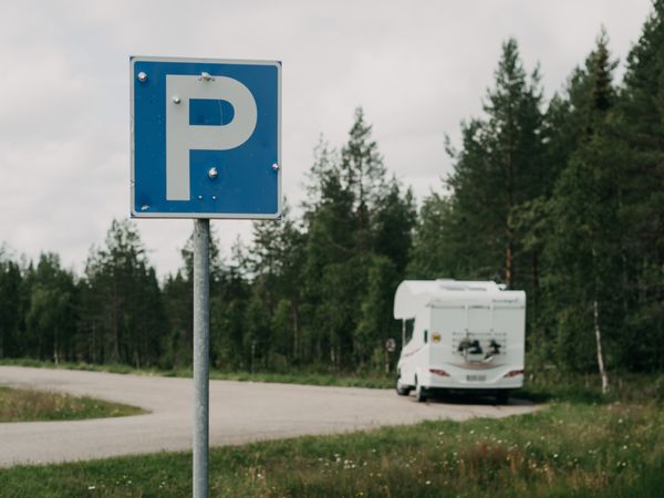 Camper car standing near parking sign