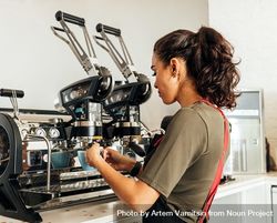 Female barista using a coffee machine to make an espresso 4OxyZb